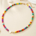 Detailed shot of multi-color beaded necklace with a white heart charm on a textured background - Colorful Hearts Style