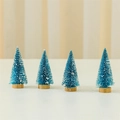 Détail de quatre mini sapins de Noël bleus de 10cm avec effet neige et socle en bois - Bleu (Ensemble de 4)