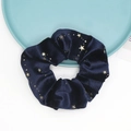 Macro detail of navy velvet hair scrunchie with gold star pattern on a blue tray - Blue