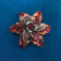Dettaglio macro di una spilla a fiore vintage rossa con placcatura in oro e strass - Stile Clematide Rosso Vino