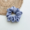 Close-up of lilac satin silk scrunchie with smooth texture on a rustic straw mat - Medium Light Purple