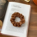 Brown fabric scrunchie with From Sheep label on an open book in soft natural light - Brown