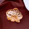 Détail d'une broche orchidée dorée à la texture métallique raffinée sur du tissu - Doré