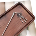Detailed shot of ethnic silver hair stick with tassel charms on a dark wood tray - F0742 Hair Stick-21# (Hollow Carved Three Column Tassel)
