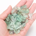 Hand holding green translucent polished crystal crushed stones for aromatherapy and healing - Green Fluorite (100g)
