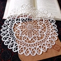 Close-up of white round lace coaster with intricate floral hollow patterns on a book - 15CM / Camellia