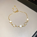Detail of adjustable gold-plated bracelet featuring white enamel flowers and cubic zirconia - Five-Petal Flower / Gold-White