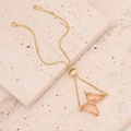 Macro detail of 18K gold-plated adjustable butterfly bracelet with champagne resin stone - Peach