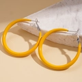 Dettaglio macro di orecchini a cerchio gialli geometrici con finitura lucida su marmo - Perno in Argento-Giallo-Grande
