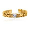 Close-up of golden mesh bracelet featuring heart-shaped crystal and floral design details - White