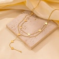 Close-up of a layered gold necklace featuring multiple heart pendants on a satin background - Double Heart Tassel Style (H1079) / Gold