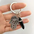 Macro detail of Hamsa Hand and black hexagonal crystal pillar on a silver keychain - Black