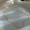 Detailed view of a sleek gold snake chain necklace on white silk with elegant shadows - Gold Wire Chain