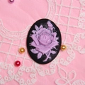 Dettaglio di cammeo con rilievo rosa viola su pizzo rosa con perle decorative - Base Nera Fiore Viola