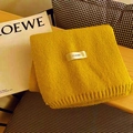 Folded yellow knitted scarf with FEIDING label on a cozy wooden background setting - Ginger Yellow
