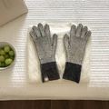 Primer plano de guantes de punto a rayas sobre un acogedor suéter de invierno texturizado - Gris