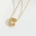 Macro shot of gold letter C pendant necklace with sparkling micro-inlaid rhinestones - Letter C