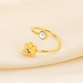 Detailed close-up of golden adjustable flower ring with zircon on beige silk fabric - US 6