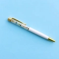 Dettaglio macro di una penna a sfera bianca con accenti dorati e interni in pietre colorate - Refill Nero 14cm / Morganite