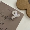 Dettaglio di un mollettone bianco cangiante con finitura perlata su sfondo di un libro - Pinza a Y Larga con Etichetta Oro