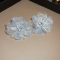 Close-up of light blue mesh flower earrings with white pearl centers on textured base - Flower Style / Blue
