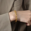Bracelet torsadé élégant plaqué or pour femme porté au poignet avec veste beige - 15+5cm / Bracelet Or