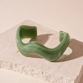 Detail of green wavy acrylic bangle with marble texture on natural stone pedestal - Light Green