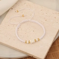 Detail of bohemian handmade beaded bracelet with gold accents and adjustable white cord - White