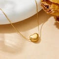 Minimalistische gouden hartjesketting van titaniumstaal in een sfeervolle lifestyle-setting - Goud