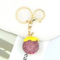 Nahaufnahme des goldenen Schlüsselanhängers mit lila Strass-Mangostanfrucht-Anhänger - Mangostan