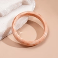 Detail of pink marble resin bangle on stone base with smooth textures and elegant lighting - White Pink