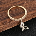Macro detail of gold butterfly pendant ring with sparkling cubic zirconia on wood surface - US 7 / Gold