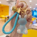 Close-up of blue resin bunny keychain with sparkling rhinestones and woven leather strap - Blue