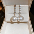 Gros plan de boucles d'oreilles dorées avec strass brillants et grandes perles blanches - Or (Tige en Argent S925)