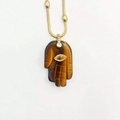 Gedetailleerd zicht op een Hamsa-handhangersketting gemaakt van natuurlijke tijgeroog - Amber