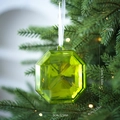 Green octagonal crystal Christmas ornament with white ribbon hanging on a tree - Green