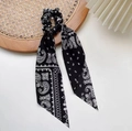 Primer plano de coletero negro con estampado paisley y cintas en bandeja de mimbre - Negro
