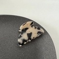 Dettaglio macro della molletta per capelli in acetato con trama bianco-nera e strass brillanti - Tartarugato