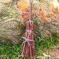 Detail of a handmade mini witch broom charm with starfish metal pendant on wood - Branch Broom + Starfish