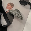 Dettaglio di un grande fermaglio per capelli in acetato con motivo marmorizzato beige e nero - Leopardo Maculato