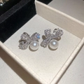 Elegante zilveren strik oorbellen met zirkonia en hangende parels op een beige doosje - Zilver (Zilveren pin)