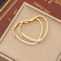 Détail de créoles en forme de cœur dorées avec pavage étincelant sur un écrin à bijoux - Blanc