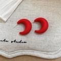 Detail view of red matte acrylic crescent hoop earrings on beige linen background - Red Moon