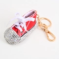 Detalle del llavero de zapatilla roja de lona con diamantes de imitación y metal - Rojo