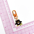 Cartoon black owl metal keychain with orange hook on a white measurement grid mat - Owl (Orange Clasp)