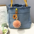 Detail of blue denim handbag with orange star charm and pink plush pom-pom keychain - Orange Red