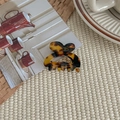 Detail of a tortoise shell heart hair claw clip with gold engraving on a woven mat - Coffee Tortoise Shell
