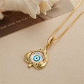 Close-up of golden Devil's Eye spade pendant on beige fabric and magazine - Spade Eyelash Eye Style