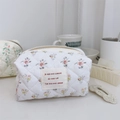 Close-up of quilted floral cosmetic bag with French script label and zip closure - Yellow and Pink Floral on White