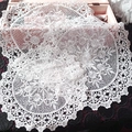 Close-up of intricate white lace embroidery texture on a round hollowed coaster mat - Lilac